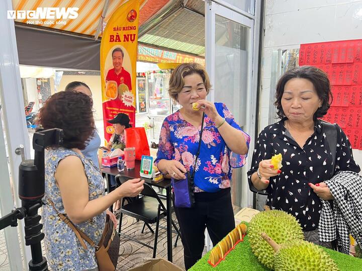 Khách hàng trực tiếp ăn thử sầu riêng tại cửa hàng trước khi quyết định mua.