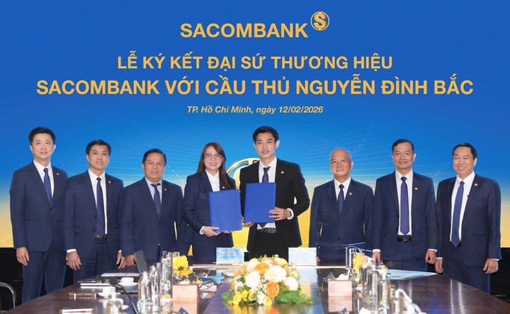 Cầu thủ Nguyễn Đình Bắc (phải) và bà Nguyễn Thị Kiều Anh (trái) - Phó Tổng giám đốc SACOMBANK thực hiện nghi thức ký kết Thỏa thuận Đại sứ thương hiệu dưới sự chứng kiến của ban lãnh đạo ngân hàng.