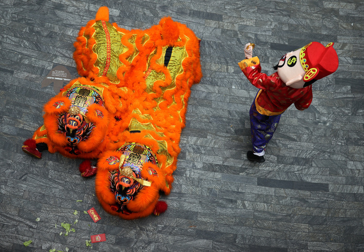Một nghệ sỹ hóa trang thành thần Tài chuẩn bị ném "tiền vàng" cho khán giả trong màn múa lân vào một ngày trước Tết Nguyên đán tại sân bay Jewel Changi, Singapore.