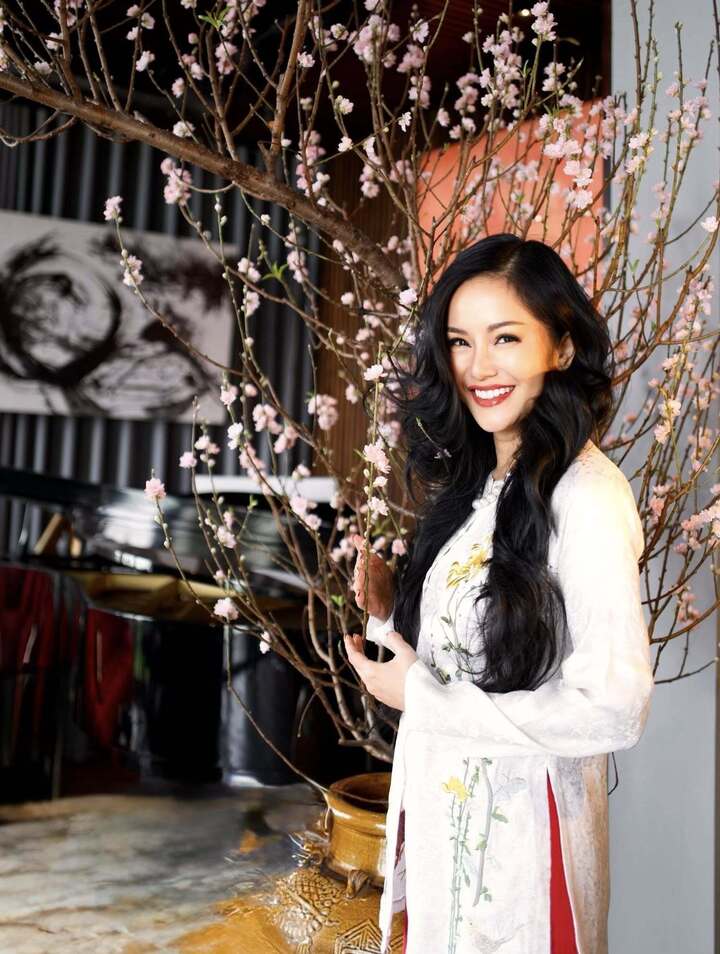 Ca sỹ Hồng Nhung diện áo dài tươi tắn bên cây đào trưng trong nhà. Cô mong muốn truyền năng lượng tích cực đến mọi người.