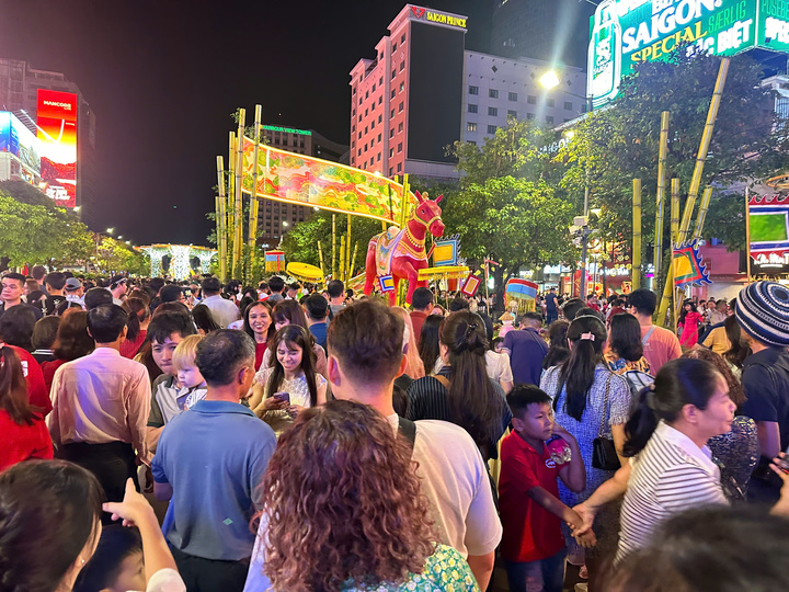 Khách chen nhau đông kín ở đường hoa Nguyễn Huệ ban đêm.