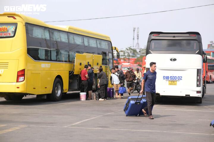 Nhân viên bến xe phối hợp với lực lượng chức năng điều tiết phương tiện trước cổng, hạn chế tình trạng dừng đỗ kéo dài gây cản trở giao thông. Nhiều người thân đứng chờ sẵn bên ngoài để đón gia đình trở lại thành phố.