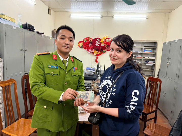 Cán bộ Công an phường Hoàn Kiếm trao trả tiền cho nữ du khách bị tài xế xe ôm “chặt chém”. (Ảnh: Công an cung cấp)