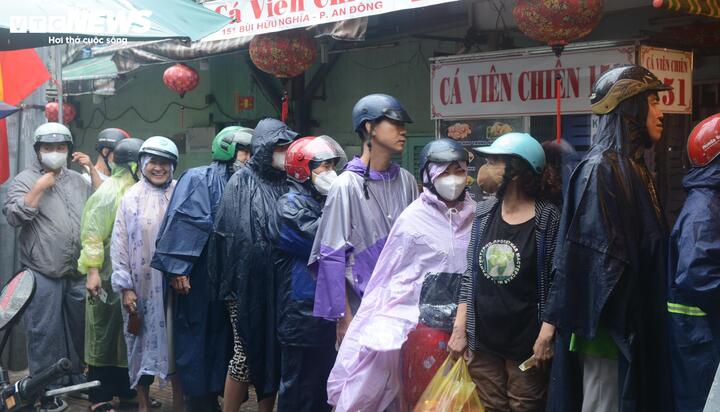 Dòng người xếp hàng dưới mưa chờ tới lượt mua hàng phía ngoài tiệm.