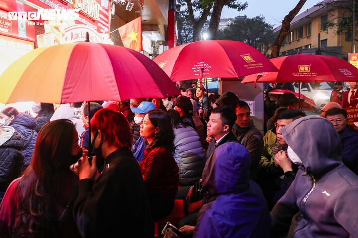 Khoảng 6h, Hà Nội xuất hiện mưa nhẹ song người dân vẫn kiên nhẫn che ô, xếp hàng dưới mưa chờ đến lượt vào mua vàng.