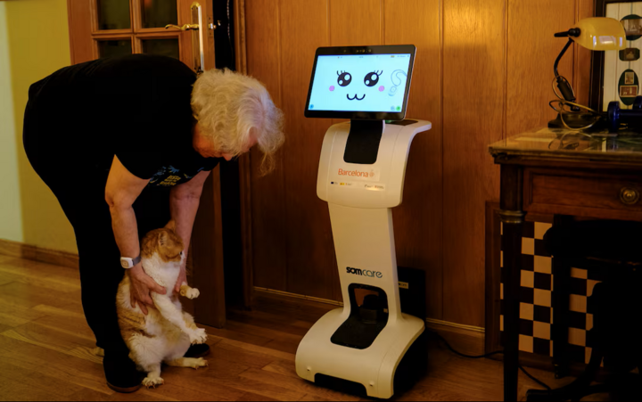 Bà Irene Veglison, 67 tuổi, ôm chú mèo tên Sweet bên cạnh con robot có biệt danh "Sandi" trong căn hộ của mình. (Nguồn: Reuters)