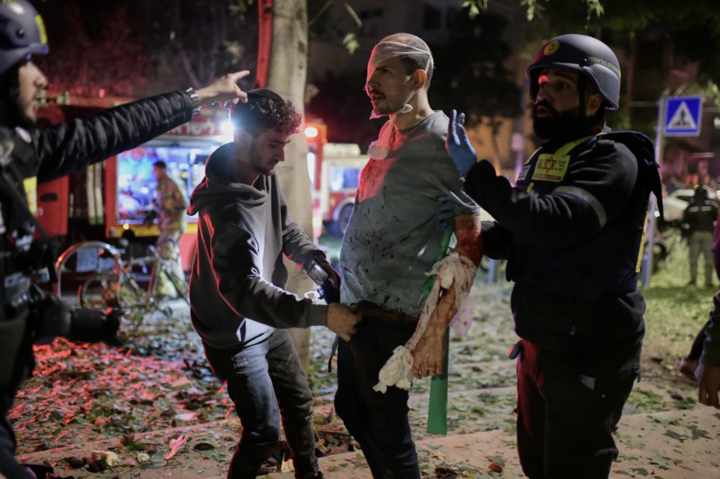 Nhân viên cứu hộ băng bó và sơ cứu cho một người đàn ông bị thương tại hiện trường vụ tấn công bằng tên lửa của Iran ở Tel Aviv, Israel. (Nguồn: AP)