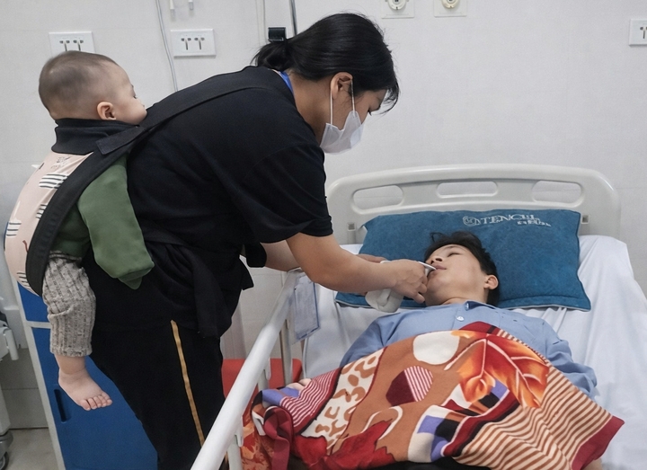 Suốt 8 tháng qua, chị Soạn bồng bế con đi khắp các bệnh viện để chăm chồng.