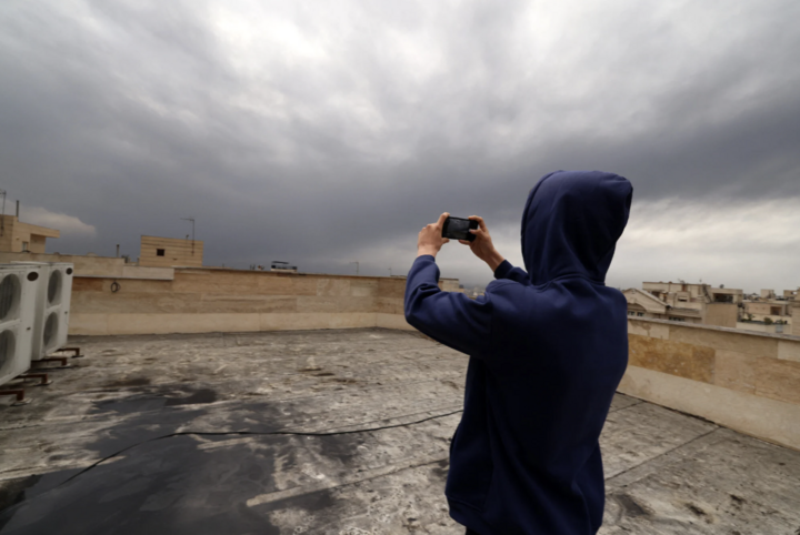 Người dân chụp ảnh khi đứng trên mái nhà phủ đầy muội than. (Nguồn: Times of Israel)