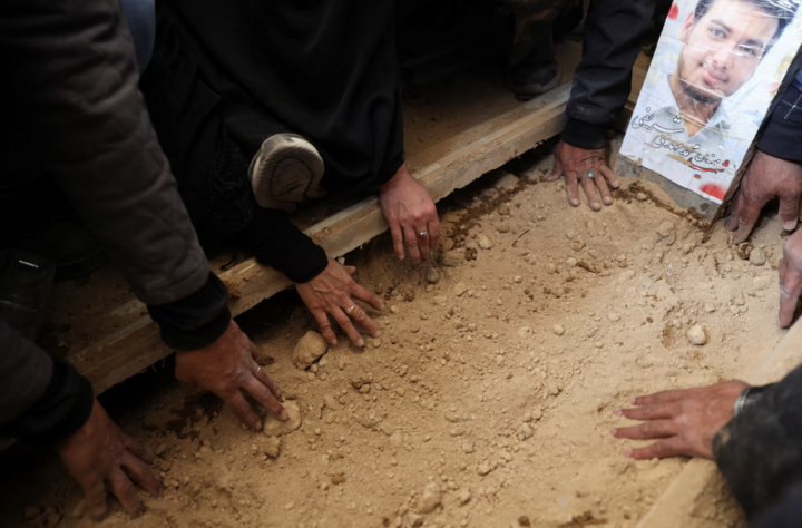 Người đưa tang đặt tay lên mộ trong lễ tang các nạn nhân tại Tehran.