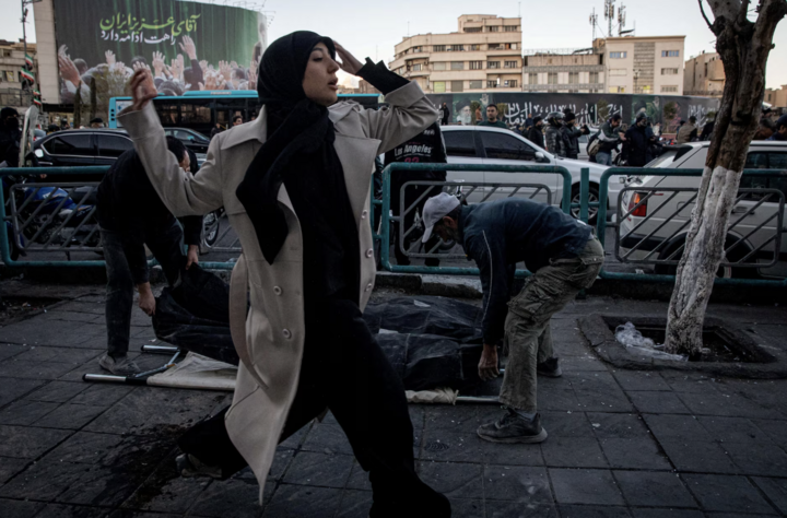 Người phụ nữ chạy ngang qua khi người dân đưa các nạn nhân ra khỏi hiện trường vụ không kích vào đồn cảnh sát tại Tehran.