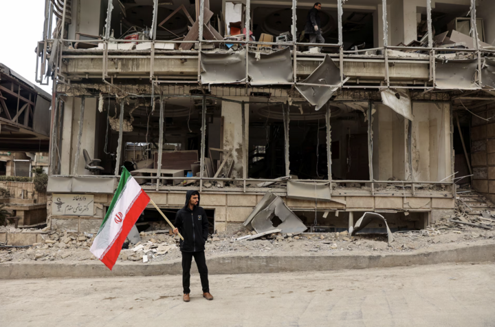 Người đàn ông cầm lá cờ Iran sau cuộc không kích nhằm vào Bệnh viện Gandhi Hotel tại Tehran.