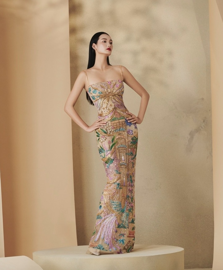Người đẹp diện chiếc đầm dài ôm sát thêu họa tiết cố đô Huế đính kết thủ công tỉ mỉ, với hình ảnh lầu son, hoa lá, chim muông xứ Huế được thêu tay bằng chỉ màu rực rỡ trên nền lụa vàng.