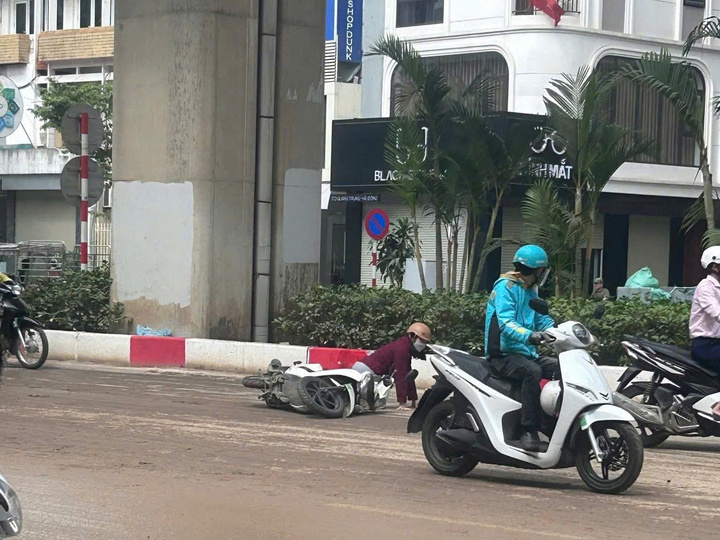 Người phụ nữ đi xe máy bị ngã ra đường do bùn đất trơn trượt.