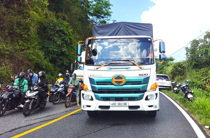 Các phương tiện xếp hàng đợi cơ quan chức năng xử lý khối đá. (Ảnh: K.P)