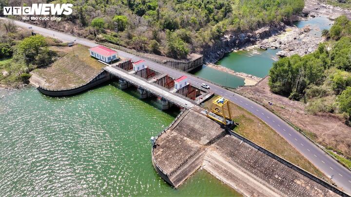 Con đập bê tông sừng sững chắn ngang dòng sông Krông H’Năng, tạo nên một hồ nước mênh mang, xanh thẳm, trải dài giữa những triền núi trùng điệp. Nhìn từ trên cao, công trình như một dải lụa khổng lồ vắt qua đại ngàn, vừa mềm mại theo đường cong địa hình, vừa vững chãi với kết cấu kỹ thuật hiện đại.