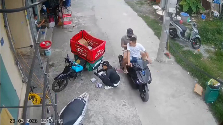 Thanh niên áo trắng đạp vào lưng shipper đang ngồi lựa hàng để giao cho khách.