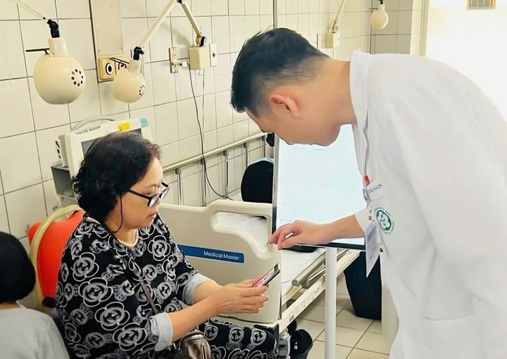 Nhân viên y tế hướng dẫn người nhà người bệnh sử dụng Bạch Mai Care - Phần mềm quản lý hồ sơ sức khoẻ “make in Vietnam”.