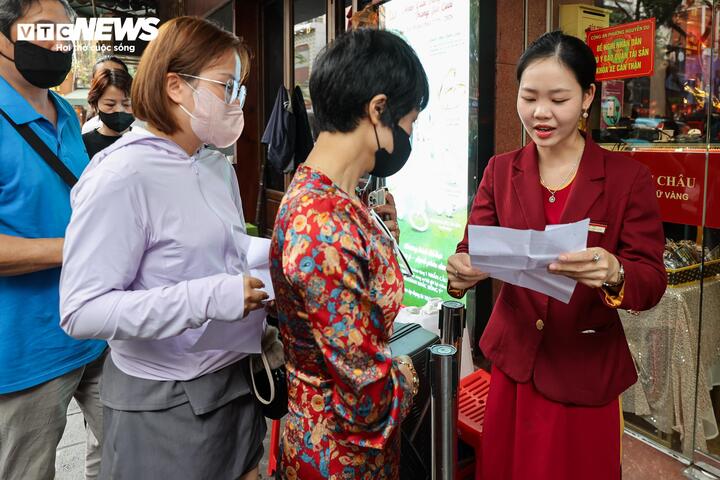 Đúng 12h, nhân viên cửa hàng kiểm tra giấy hẹn và lần lượt cho khách đã có giấy nhận vàng vào bên trong để thực hiện giao dịch.