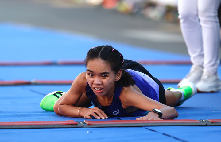 Nữ vận động viên không bỏ cuộc, vươn tay trườn qua vạch đích.