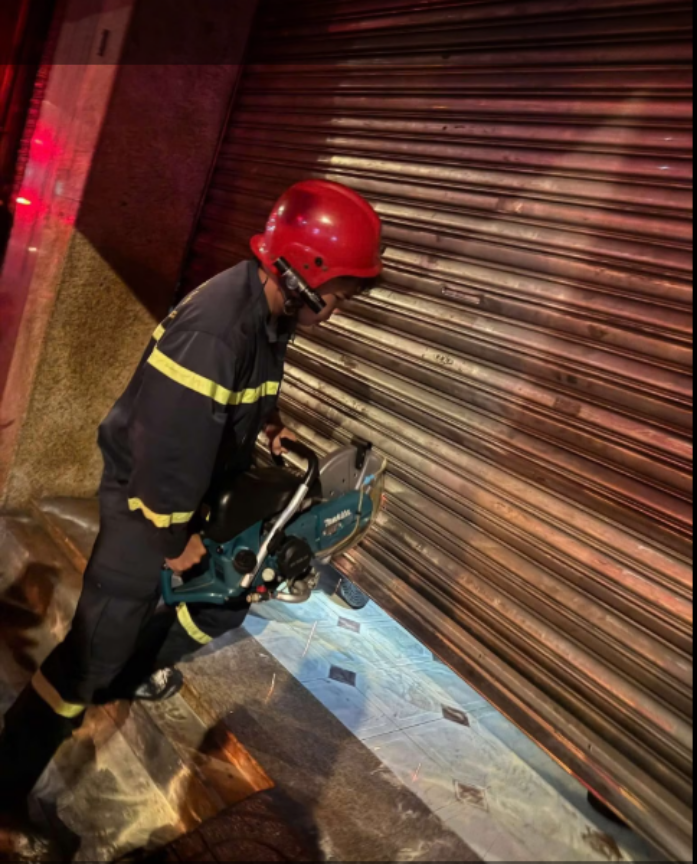 Lực lượng cứu hộ dùng cưa cắt cửa cuốn cứu người.