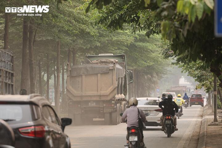 Chỉ cần một xe tải đi qua, cả tuyến phố lập tức bị bao phủ bởi màn bụi dày đặc. Từng đoàn xe công trình nối đuôi nhau chạy rầm rập, khiến các phương tiện phía sau hứng trọn lượng bụi phát tán.