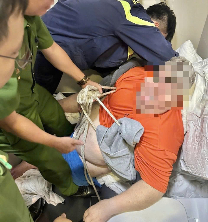 Lực lượng chức năng giải cứu nam du khách mắc kẹt trong phòng vệ sinh. (Ảnh: Đ.N)