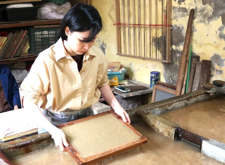 Giữa xưởng nhỏ thoang thoảng mùi vỏ dó, đôi tay chị Huyền miệt mài bên bể bột, thoăn thoắt xeo từng tờ giấy mỏng nhẹ.