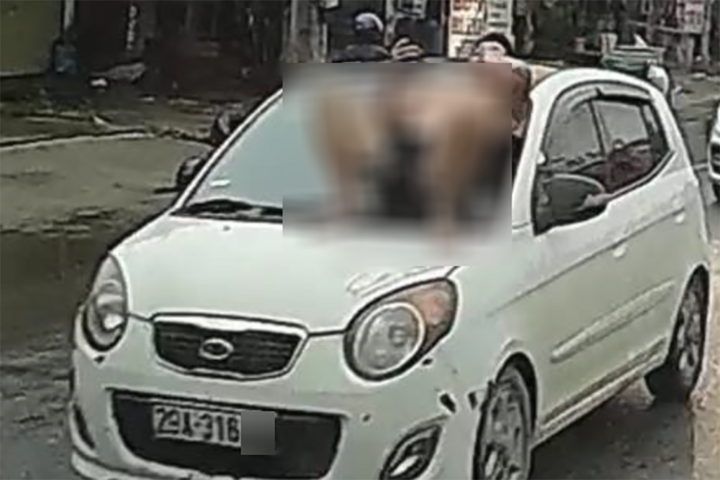 Người đàn ông nằm trên nắp capo ô tô đang chạy.