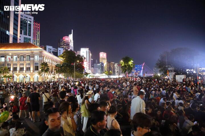 Tại công viên bến Bạch Đằng, nhiều gia đình mang theo bạt, áo mưa, đồ ăn trải trên thảm cỏ để ăn uống, chờ đến 21h thưởng ngoạn màn pháo hoa từ bờ sông Sài Gòn và các sà lan trên sông.