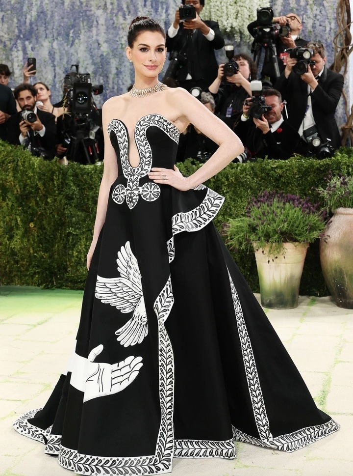 Anne Hathaway thanh lịch trong chiếc váy dạ hội bằng lụa đen, với đường viền cổ xẻ sâu và đường xẻ tà cao. Thiết kế như một bức tranh được tô điểm bằng những họa tiết vẽ tay tinh xảo của Peter McGough.