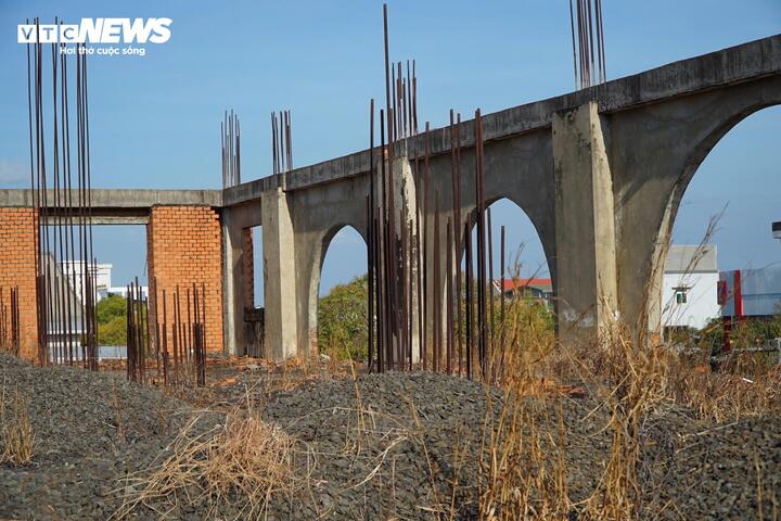Cốt thép lộ thiên ở toà nhà đã hoen gỉ, đá xây dựng bị đổ chỏng chơ, cỏ dại mọc xung quanh.