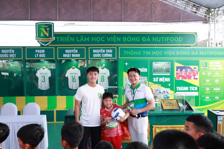 Một cầu thủ nhí hạnh phúc khi được chụp hình với Quốc Việt.
