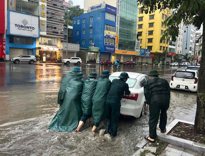 Lực lượng chức năng hỗ trợ người dân di dời thiết bị điện, tài sản có giá trị khỏi khu vực ngập úng.