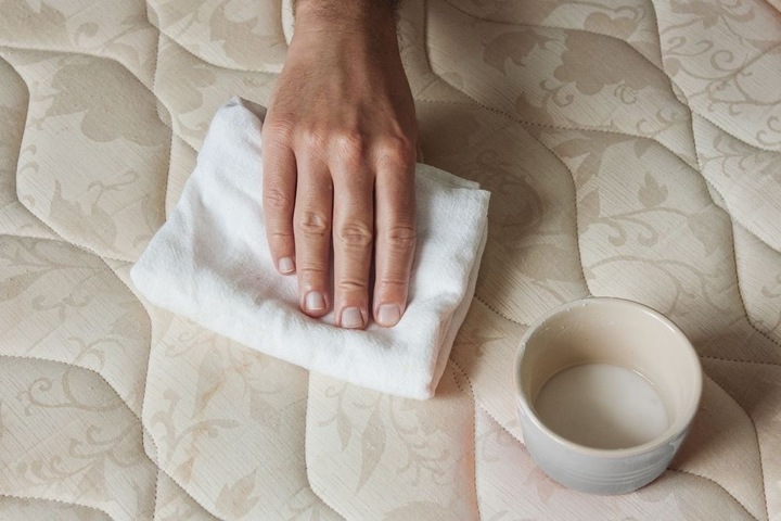 Dùng khăn sạch chấm nhẹ vào hỗn hợp giấm, nước rửa bát để vệ sinh nệm. (Ảnh: HomeWorld)