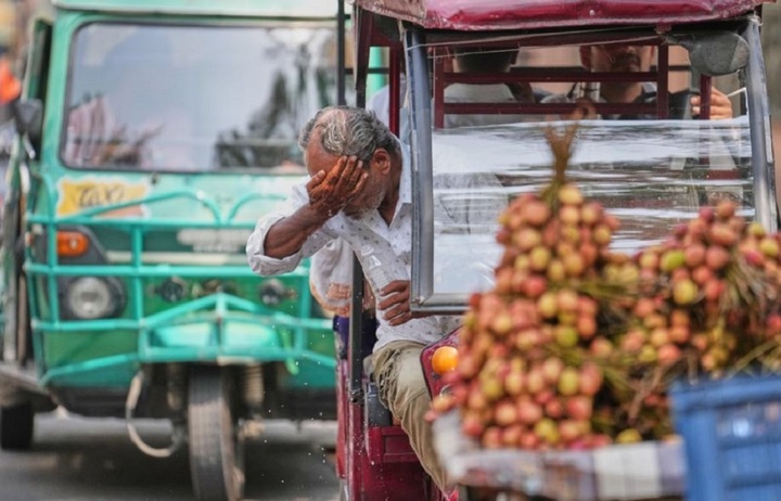 Một người lái xe ba bánh điện vẩy nước lên mặt để hạ nhiệt dưới cái nắng gay gắt ở Lucknow, Ấn Độ. (Ảnh: AP)
