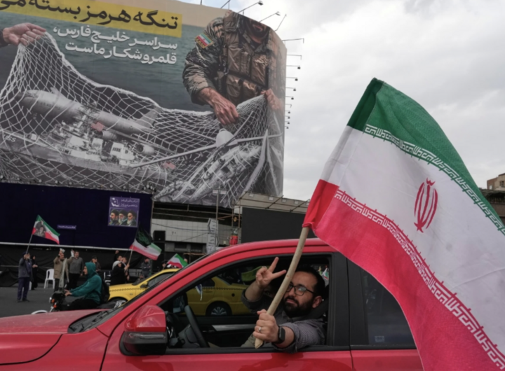 Một người dân Iran cầm quốc kỳ trên đường phố. Ảnh: AP