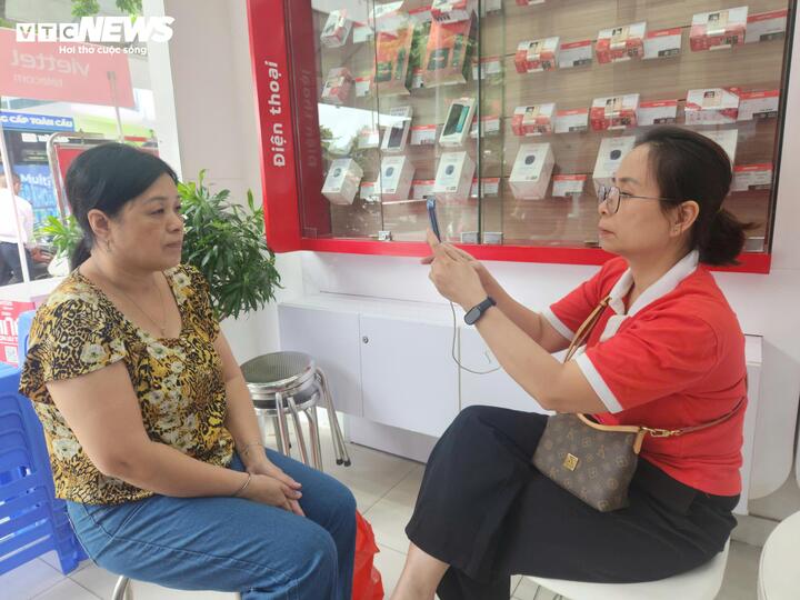 Bà Lương Thị Hòa được nhân viên Viettel hỗ trợ xác thực sinh trắc học. (Ảnh: Minh Hoàn)