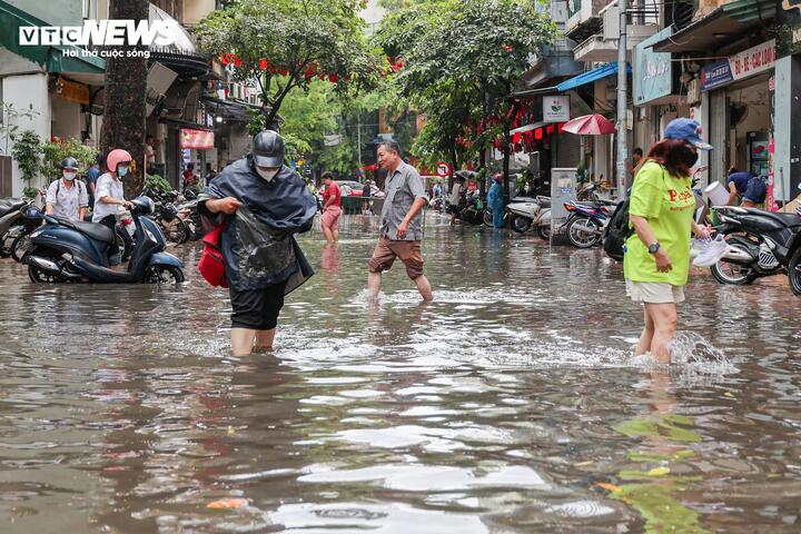 Người dân chật vật đi lại qua khu vực dềnh nước trên phố Hòe Nhai.
