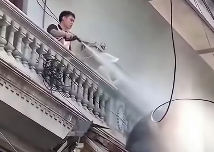 Nguyễn Duy Mạnh xịt nước vào người thợ đang tháo dỡ. (Ảnh: Cắt từ clip)
