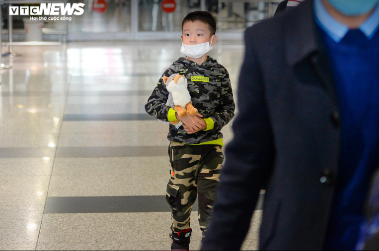 Một bé trai ngơ ngác ôm theo thú bông khi bước ra sảnh sân bay.