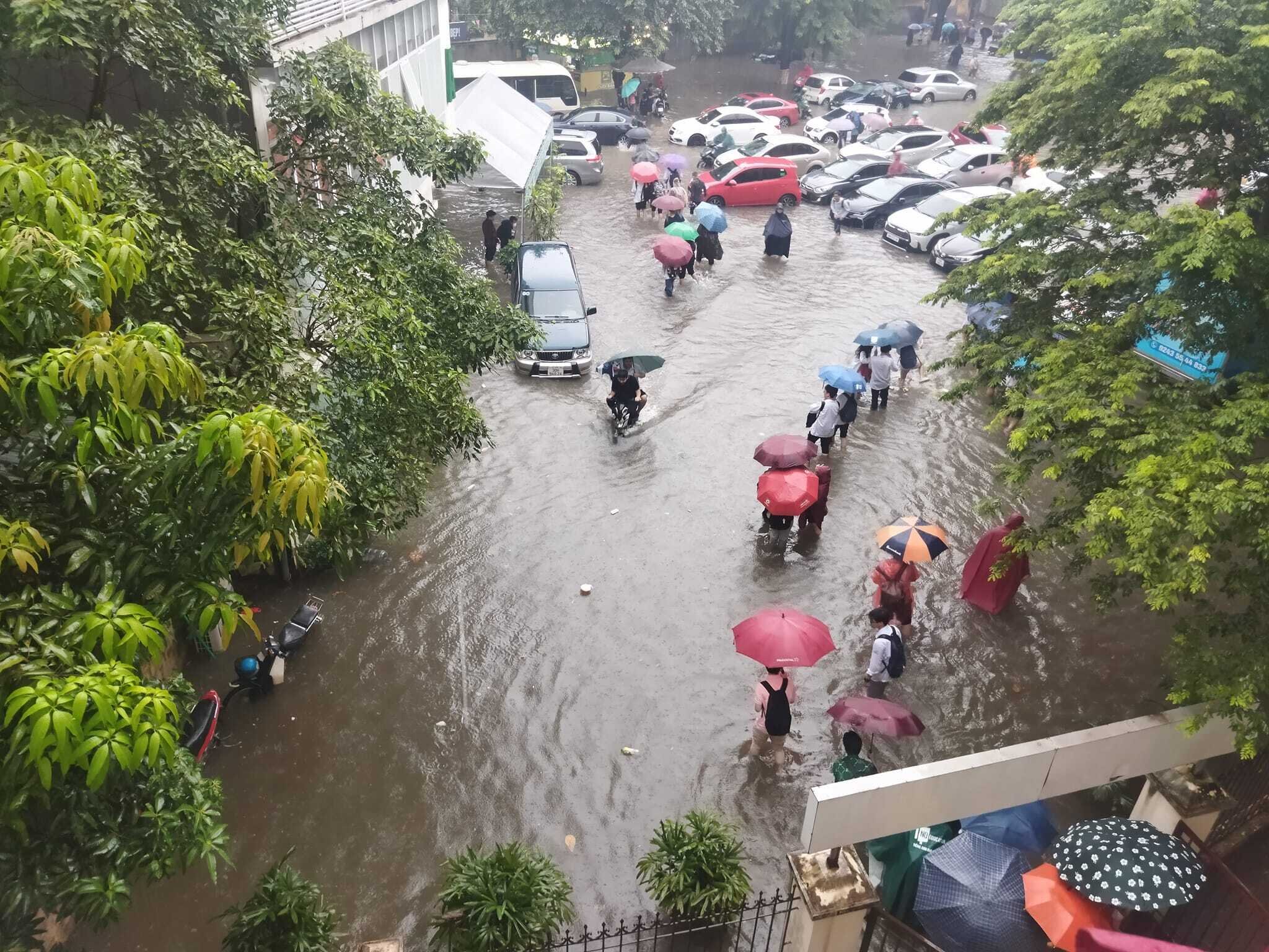Sau giờ tan trường, nhiều học sinh bì bõm lội nước trở về nhà. Đây là khung cảnh không còn xa lạ đối ở Hà Nội mỗi lần mưa lớn. (Ảnh: G.D)
