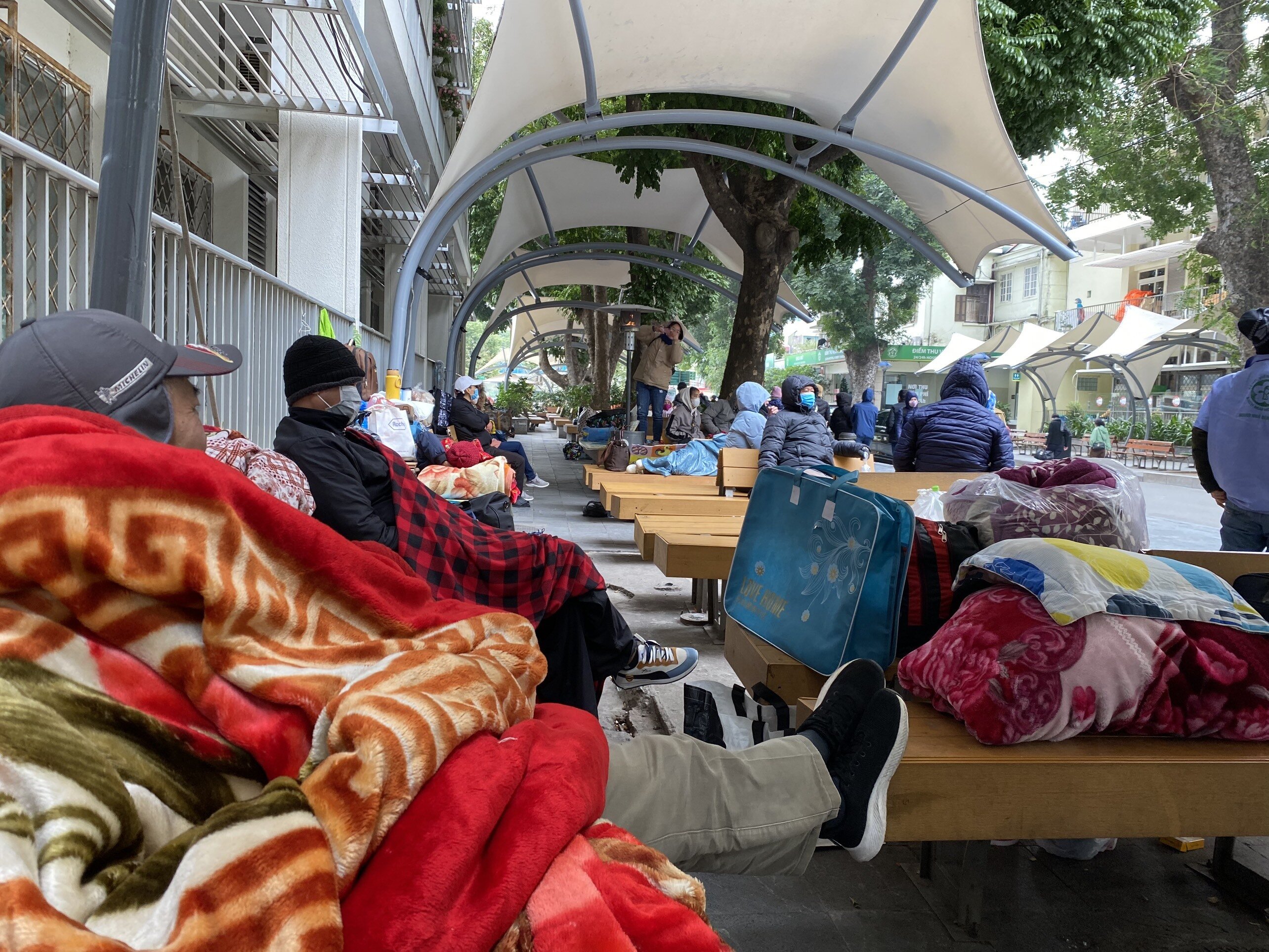 Tại Bệnh viện Bạch Mai, nhiều người thân siêng người bị bệnh ngồi ngoài cộng đồng mong chờ.