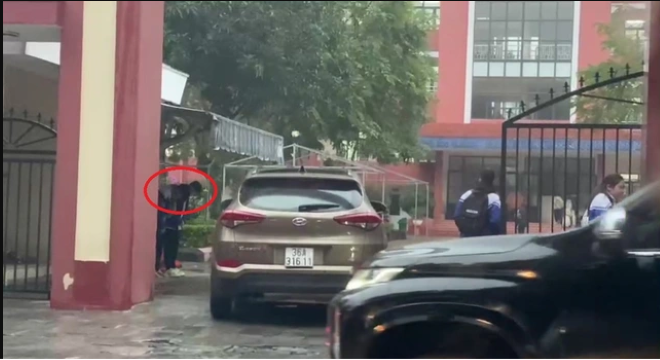 Hình ảnh 2 em học sinh cúi chào khi một chiếc ôtô đi vào sân trường. Ảnh cắt từ clip