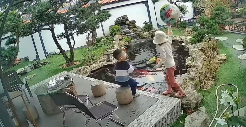 Hai bé chơi đùa gần hồ cá. (Ảnh chụp màn hình)