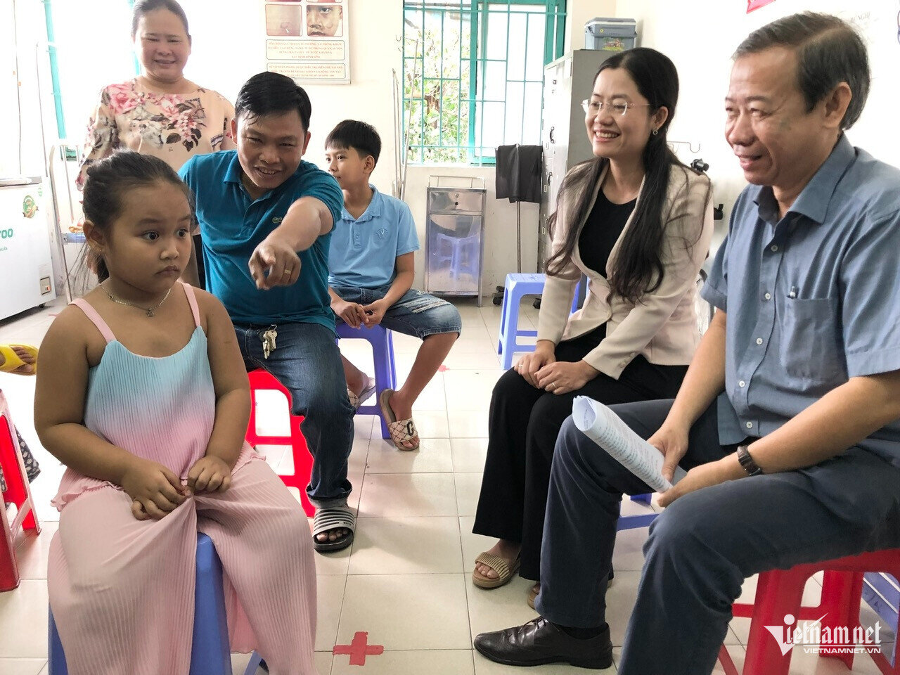 Phó giám đốc Sở Y tế TP.HCM Nguyễn Văn Vĩnh Châu (ngoài cùng bên phải) hỏi thăm trẻ trước khi tiêm ngừa. (Ảnh: Bạch Dương)