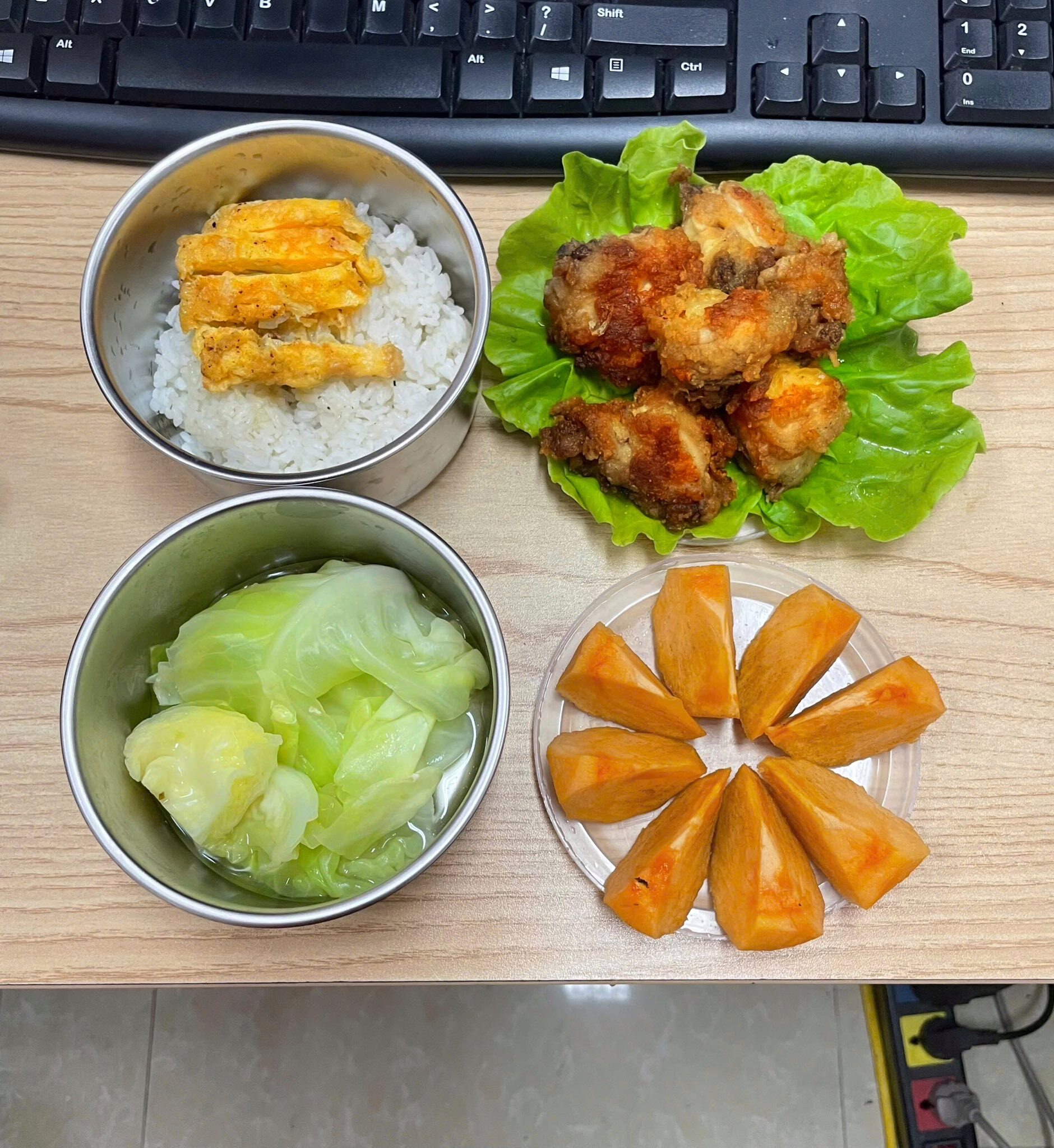 Hộp cơm văn phòng gồm gà viên rán giòn bên ngoài, mềm bên trong, trứng rán vàng ươm, thơm lừng, tráng miệng bằng hồng giòn.
