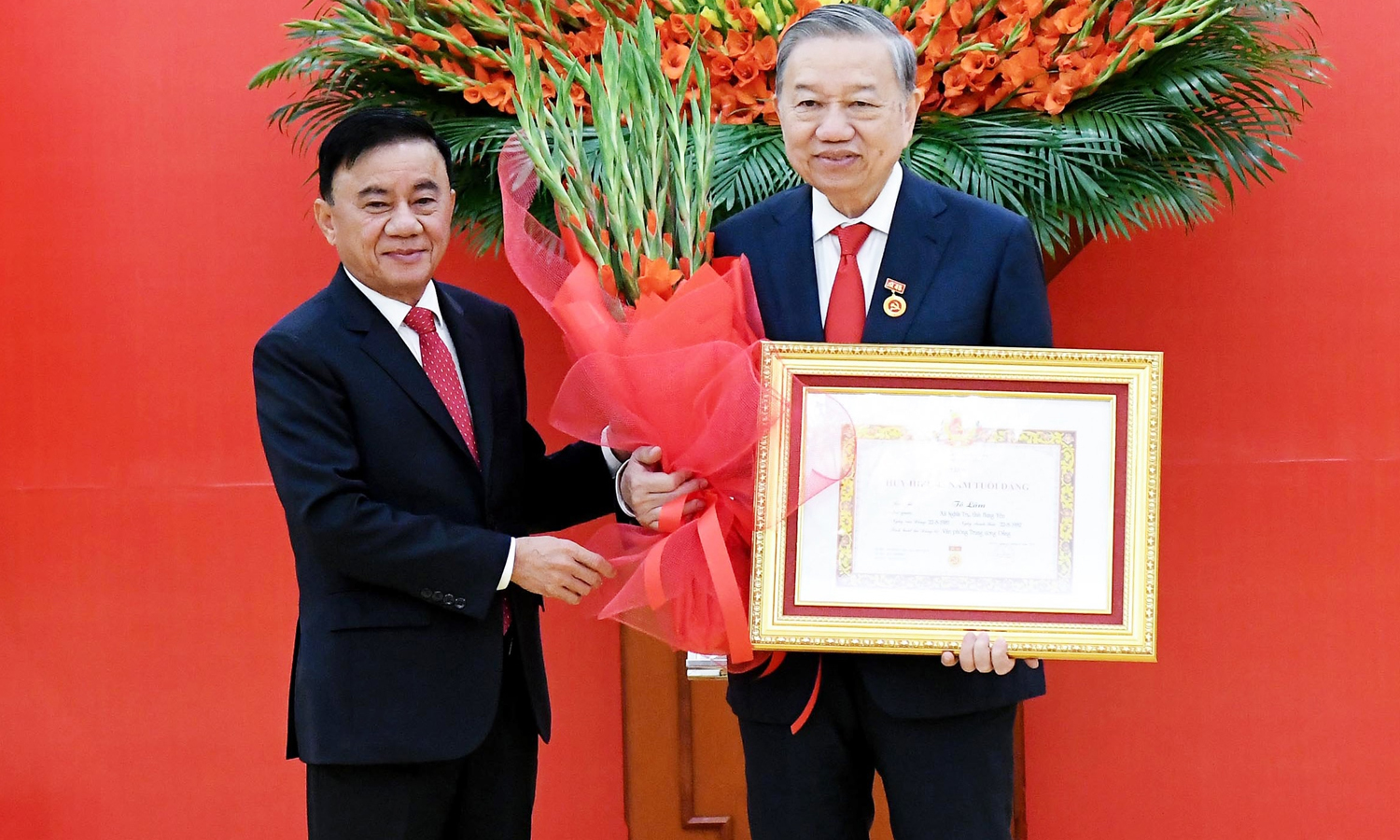 Thường trực Ban Bí thư Trần Cẩm Tú trao huy hiệu 45 năm tuổi Đảng và tặng hoa chúc mừng Tổng Bí thư Tô Lâm. (Ảnh: Lâm Hiển)